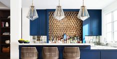 a kitchen with blue cabinets and bar stools in front of the countertop area