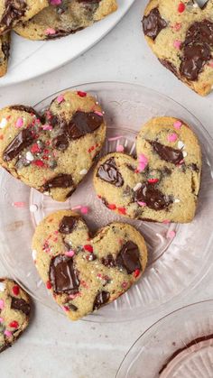 chocolate chip heart cookies with sprinkles on a clear plate next to plates