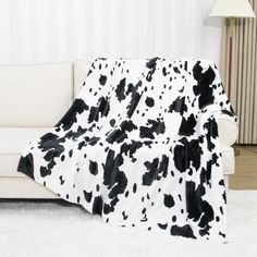 a black and white cow print blanket sitting on top of a couch next to a lamp