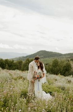 a bride and groom standing in the middle of a field