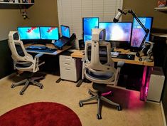 three computer monitors sitting on top of desks in front of a red round rug