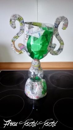 a green glass trophy sitting on top of a black stove burner covered in money