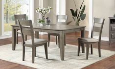 a dining room table and chairs in front of a window with white flowers on it