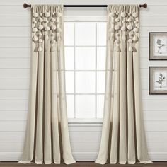 the curtains are hanging in front of a window with white walls and wood flooring