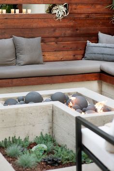 an outdoor fire pit surrounded by pillows and plants