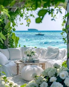 an outdoor seating area with white furniture and flowers