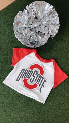 Take your game day style to the next level with our Ohio Crop Baby Tee, perfect for college game day! Its stretchy fabric makes it the perfect option for a comfy game-day look. Ohio crop tee White/Red Baby tee 95% Polyester, 5% Spandex. Cropped Fit Measurements/Sizing: (Approximate. Measured lying flat.) **2-3" stretch throughout. S- Bust 30" Length 14 1/2" M-Bust 32" Length 15" L- Bust 34" Length 15 1/2" Model Specs: Emily is wearing a size small in the photo.How will this item fit you? Check out our MODEL SPECS (Typical Sizing - Karli: S-Size 5/26 - 5ft 2in, Emily: S-Size 3/25 - 5ft 5in, Syd: L/XL- Size 15/ - 5ft 8in)Need help with sizing? No problem! Join our VIP group on Facebook, Everyday Chic Boutique VIP Insiders to chat directly with our team and other customers just like you.Packa Varsity Team-colored Tops For Game Day, Collegiate Tops With Team Logo For Game Day, Team Colors Tops For Game Day, Varsity Tops For Cheerleading During Football Season, Varsity Style Tops For Football Season Game Day, Varsity Style Tops For Game Day, Varsity Logo Print T-shirt For Game Day, College Stretch T-shirt With Letter Print, Collegiate Team-colored Tops For Baseball Season