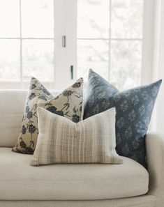 four pillows on a couch in front of a window