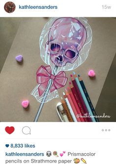 a drawing of a skull with a pink bow on it's head and some colored pencils next to it