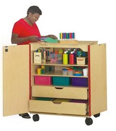 a man standing behind a wooden cabinet with lots of craft supplies on top of it