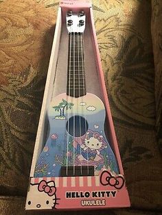 a hello kitty ukulele is sitting on a couch with its head in the box