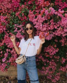 a woman standing in front of pink flowers