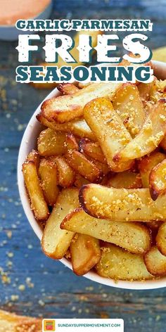 a white bowl filled with fries sitting on top of a wooden table covered in seasoning