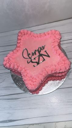 a cake with pink frosting and black writing on it sitting on top of a table