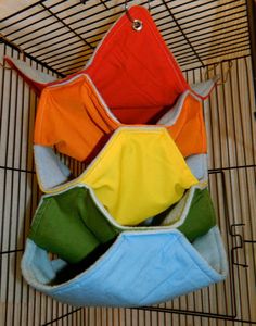 four different colored purses are in a small cage on top of a bamboo floor