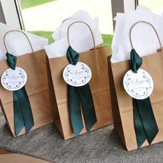 three brown paper bags with green ribbons on them