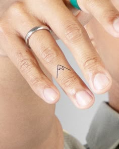 a woman's left hand with a small tattoo on her right ring and the other half of her finger