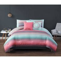 a bed in a room with grey walls and pink and blue comforter sets on it