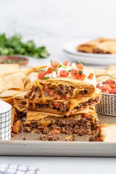 some tacos stacked on top of each other in front of tortilla chips