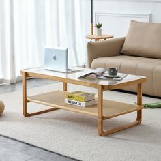 a living room with a couch, coffee table and laptop on top of the table