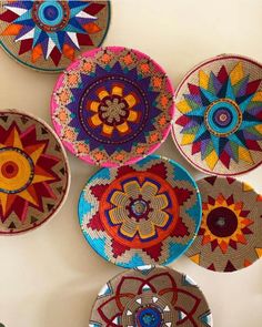 colorful baskets are hanging on the wall with circular designs in different colors and sizes, all made from woven material