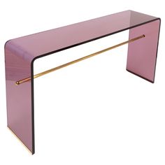 a pink glass table with gold legs