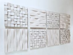 four white tiles are arranged on the wall, each with different lines and shapes in them