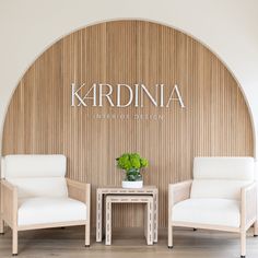 two white chairs sitting next to each other in front of a wall with the name kardinia written on it