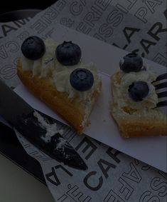 two pieces of cake with blueberries and whipped cream on top sitting next to a knife