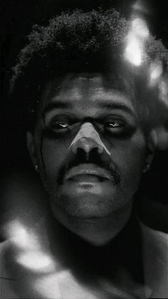 a black and white photo of a man with his face painted like a bird,