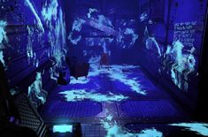 a dark room with blue lights and white clouds on the floor