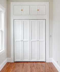 an empty room with white closets and wood floors