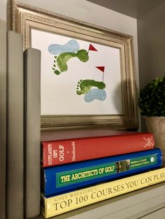 books are stacked on top of each other in front of a framed golf player's foot print