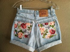 a pair of shorts with flowers on them hanging from a hanger in front of a wall