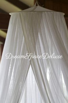 a canopy bed with white drapes hanging from it's sides and the words dream grace deluxe above it