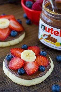 two cookies with fruit on top and nutella spread in the background next to them