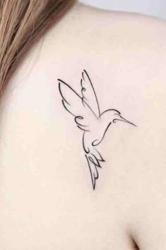 a woman's back shoulder with a small bird tattoo on the left side of her neck