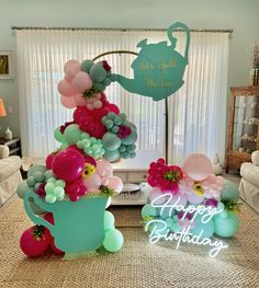 there is a birthday cake made out of balloons in the shape of a watering can