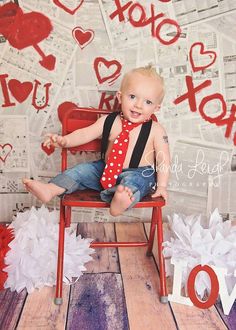 a baby sitting in a chair wearing a red tie and blue jeans with the word love spelled on it