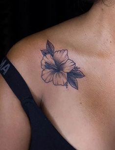 a woman's shoulder with a flower tattoo on the left side of her chest