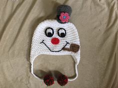 a crocheted white hat with a red flower on top and a brown nose