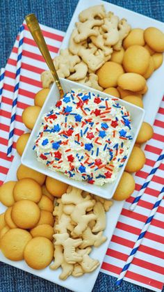 two plates filled with cookies and desserts on top of a blue table cloth next to red, white and blue strawberries