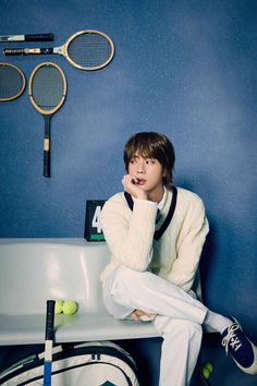 a person sitting on a chair with tennis rackets and balls in front of them