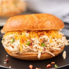 a close up of a chicken sandwich on a plate with other food items in the background