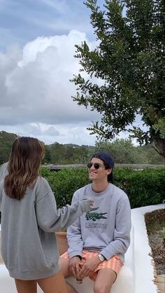 a man sitting on top of a white bench next to a woman in shorts and a sweatshirt