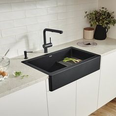 a kitchen sink sitting on top of a counter next to a potted plant in a vase