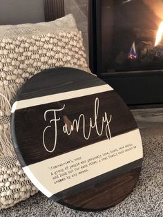 a family sign sitting on the floor next to a fire place with pillows and blankets