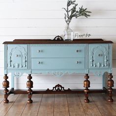 an old dresser painted blue with wood trimmings and flowers in a vase on top