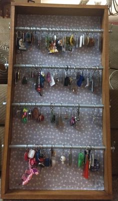 a wooden display case filled with lots of key chains and hanging jewelry on it's sides