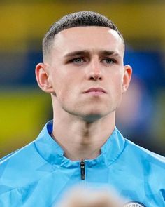 a close up of a soccer player wearing a blue shirt and looking at the camera